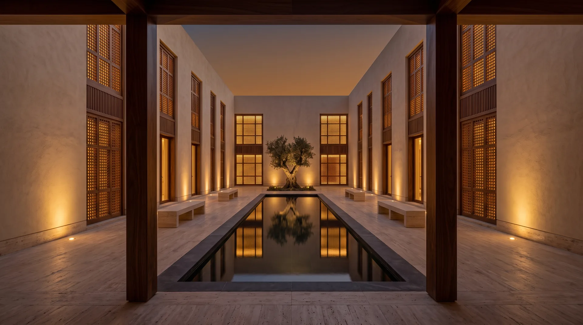 A courtyard at dusk: a reflecting pool and an olive tree between lit timber mashrabiya screens